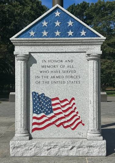 A stone memorial at Calverton National Cemetery honoring those who served in the Armed Forces of the United States, featuring a painted U.S. flag.